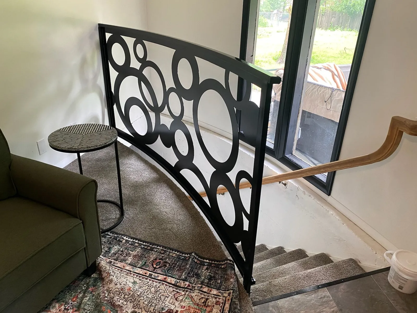 Custom black ornamental metal railing installed along an interior staircase